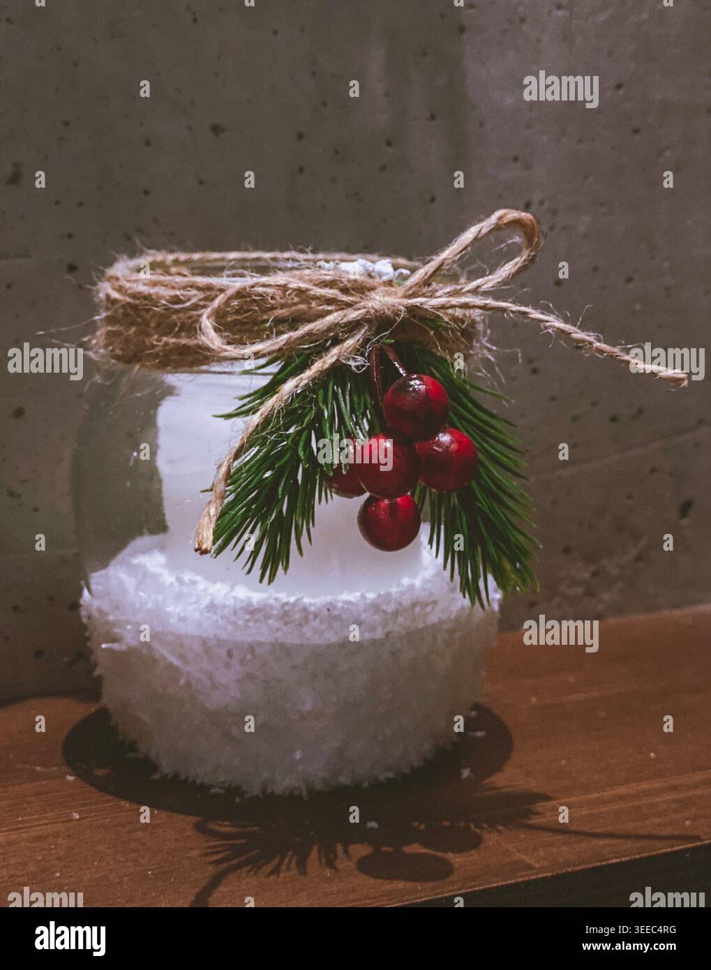 Bougie de Noël dans un pot en verre avec branche de pin, baies rouges et décoration de ficelle rustique Banque D'Images