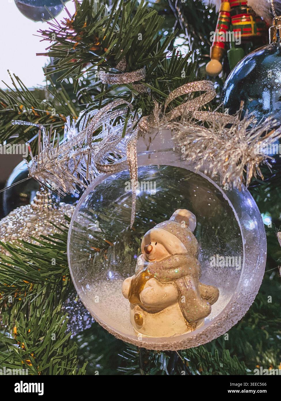 Ornement bonhomme de neige à l'intérieur de la boule de verre sur l'arbre de Noël, gros plan festif cosy étincelant - Image de stock capturée avec un smartphone