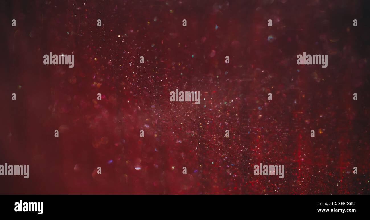 Scintillement flou. Points scintillants légers. Poudre arc-en-ciel éclatante en mélange de ruisseaux roses rouges. Couleur d'art bokeh luminosité abstrait brillant fond. Banque D'Images