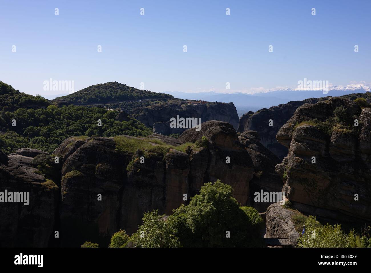 vue panoramique sur les anciens monastères perchés au sommet des piliers rocheux de grès imposants dans les météores, grèce, sous un ciel bleu clair avec m enneigé lointain Banque D'Images