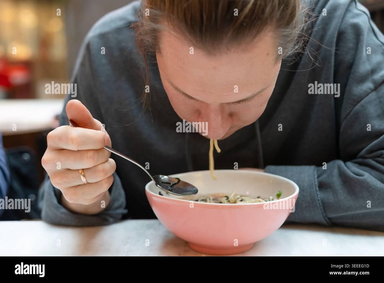 Homme savourant un bol de nouilles dans un restaurant asiatique confortable. Guy appréciant la nourriture de confort chaud avec une expression satisfaite dans un restaurant décontracté. Ambiance décontractée du bar à nouilles avec délicieux repas Banque D'Images