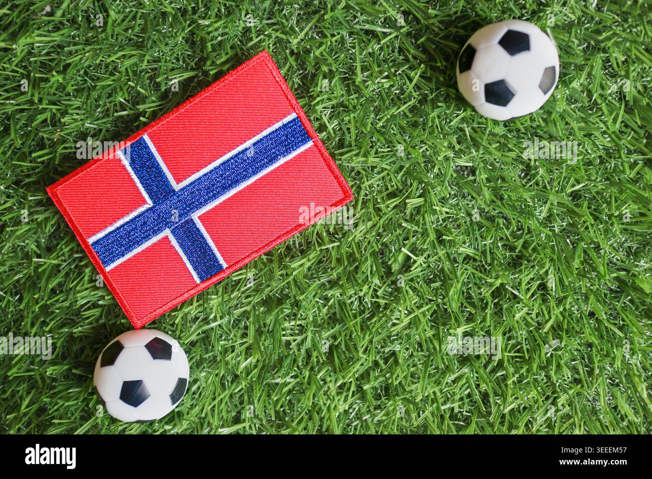 Concept de football norvégien avec drapeau national brodé et ballons de football sur herbe verte symbolisant l'esprit du tournoi mondial. Banque D'Images