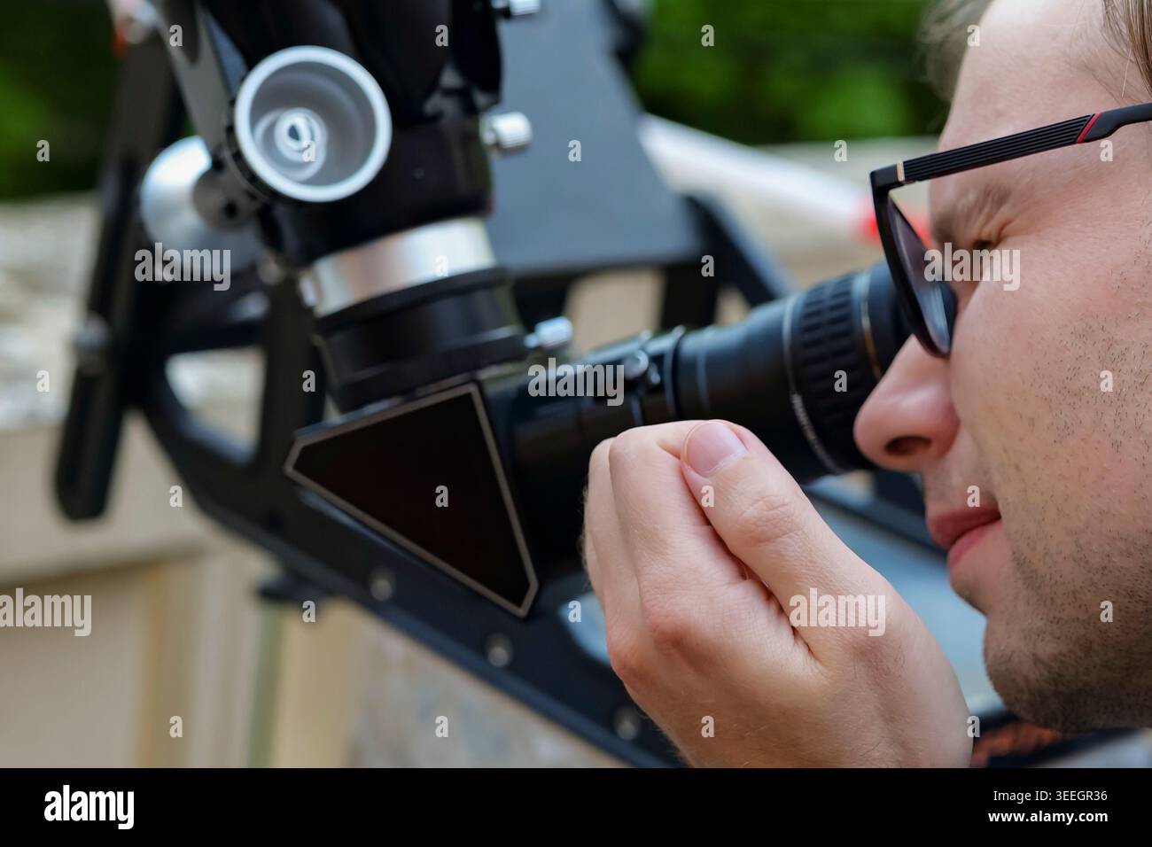 Personne regardant à travers un oculaire de télescope astronomique dans une vue rapprochée, démontrant l'équipement d'astronomie amateur en cours d'utilisation. Banque D'Images
