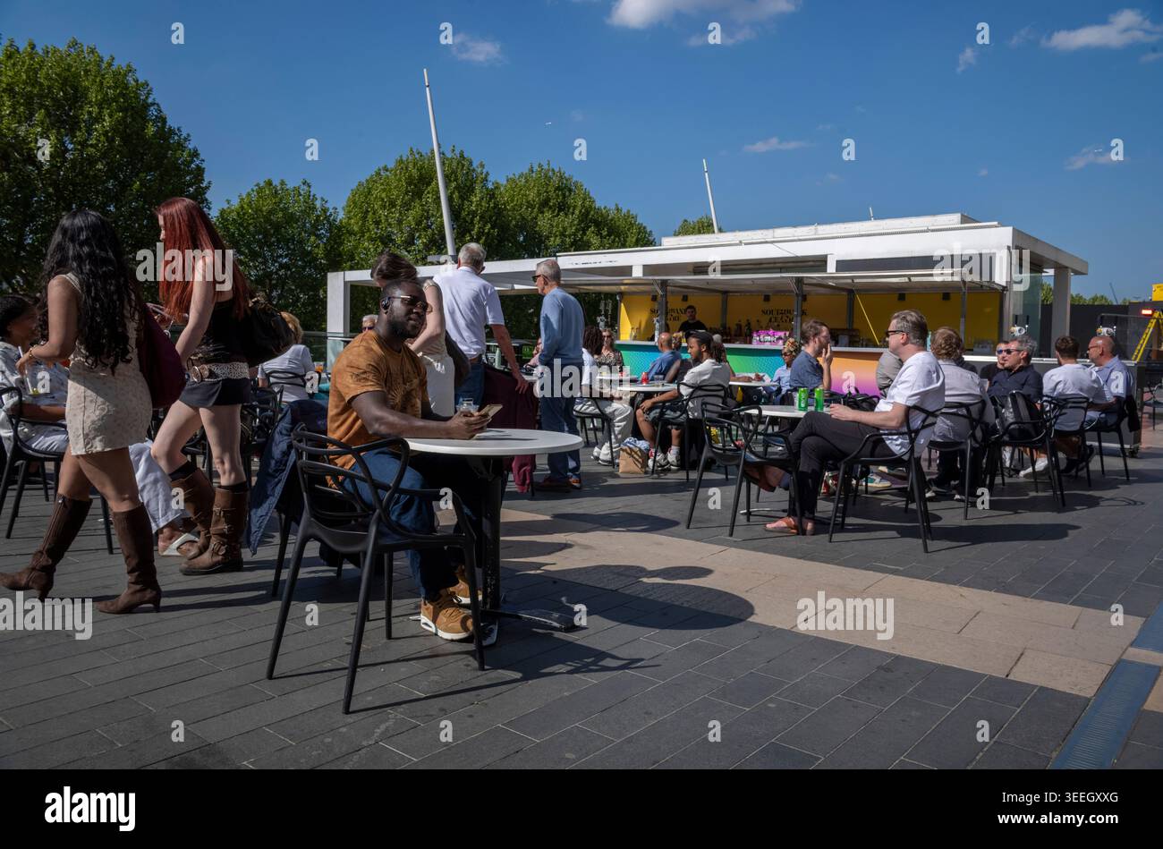 Les touristes profitent du soleil de l'après-midi tout en étant assis devant le Royal Festival Hall le long de la Southbank, situé sur la Tamise à Londres, Royaume-Uni Banque D'Images
