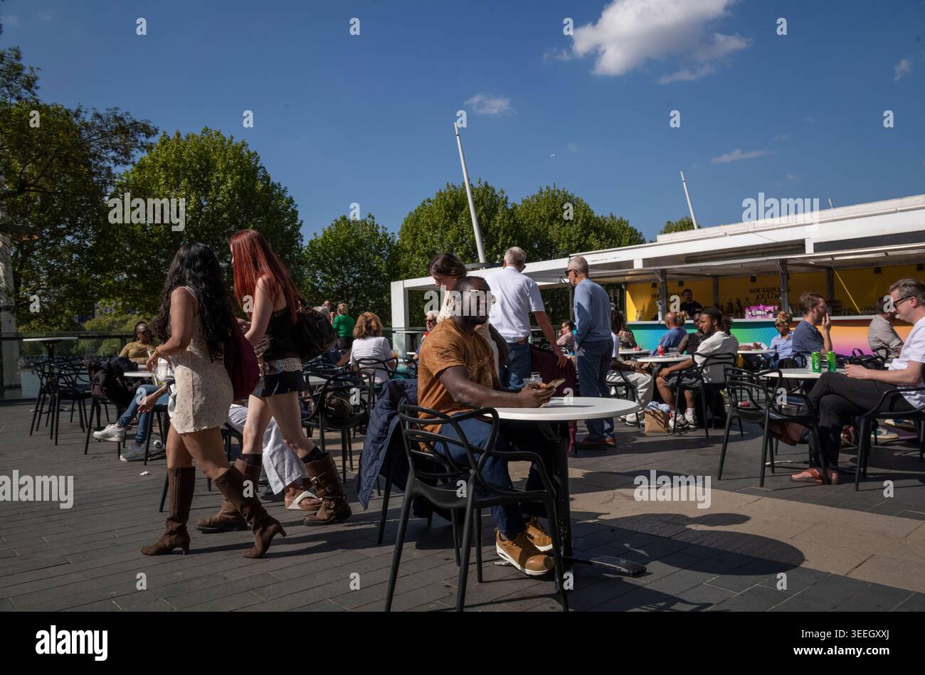 Les touristes profitent du soleil de l'après-midi tout en étant assis devant le Royal Festival Hall le long de la Southbank, situé sur la Tamise à Londres, Royaume-Uni Banque D'Images