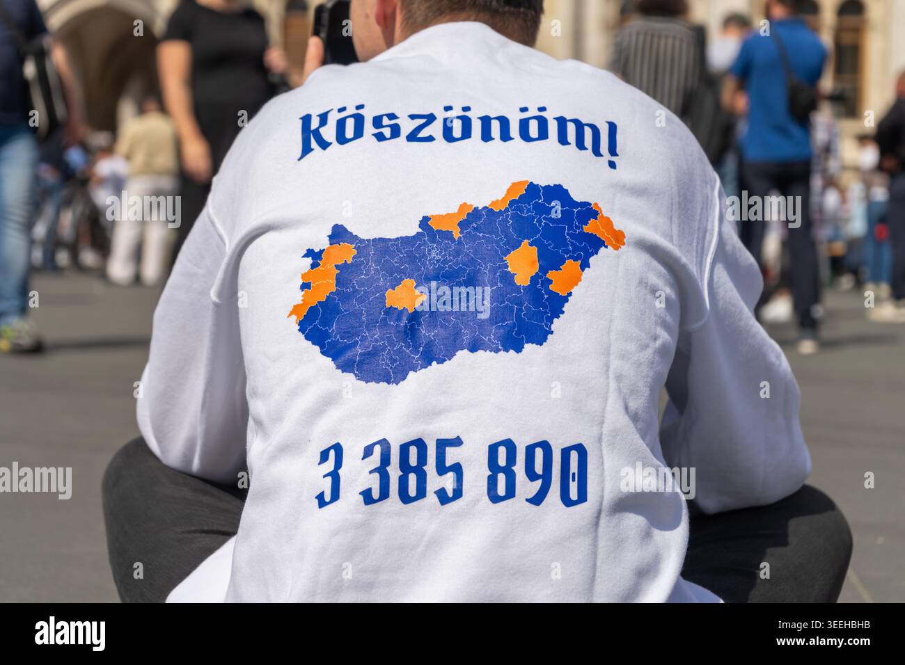 Un partisan du Parti Tisza portant la carte électorale hongroise de 2026 regarde la session inaugurale du parlement sur la place Kossuth à Budapest. Banque D'Images