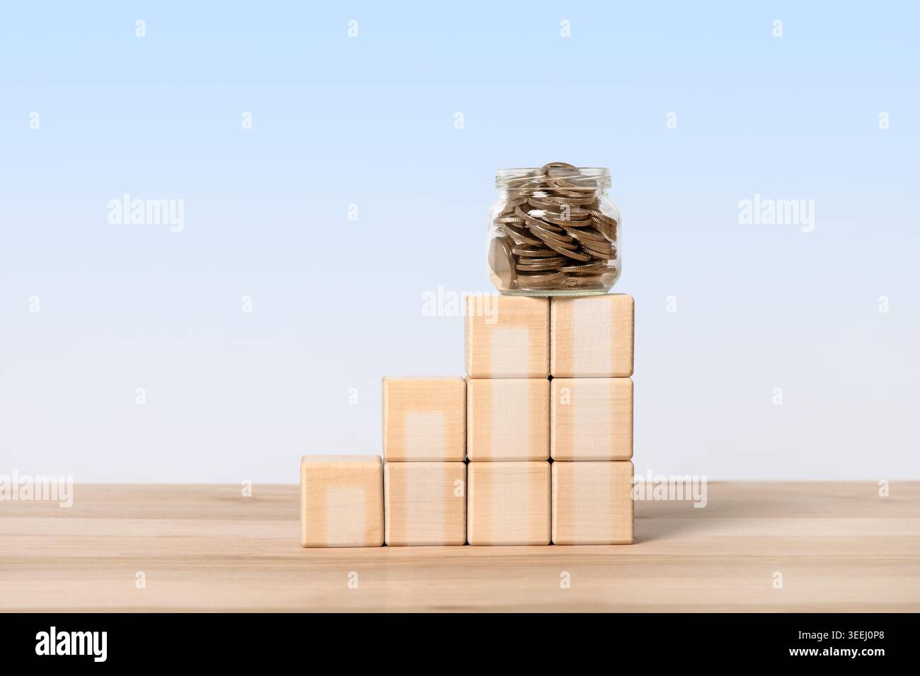 Piles de pièces de monnaie avec pot en verre avec pièces de monnaie et bloc en bois sur fond bleu. Augmentation des taux d'intérêt. Économie mondiale, faillite et maîtrise de l'inflation. Concept commercial Banque D'Images