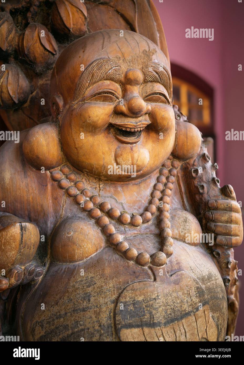 Détail en gros plan d'une sculpture de statue de Bouddha riant en bois altérée avec un collier de perles de prière, George Town, Penang, Malaisie Banque D'Images