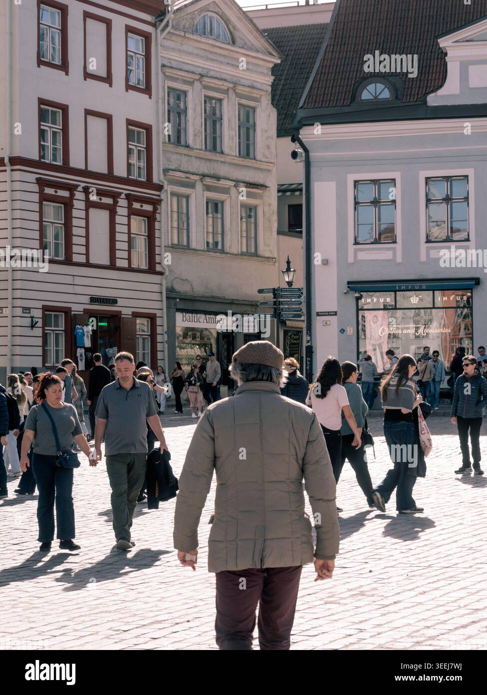 Les piétons traversent la place pavée ensoleillée de la vieille ville de Tallinn par une chaude journée de printemps, Estonie Banque D'Images