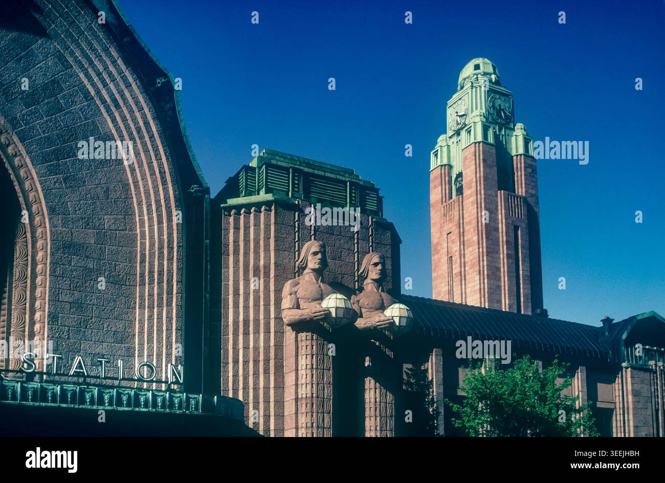 Gare de style rétro rétro d'Helsinki avec tour de l'horloge néo-classique et figures en pierre tenant des lampes Helsinki Finlande Banque D'Images