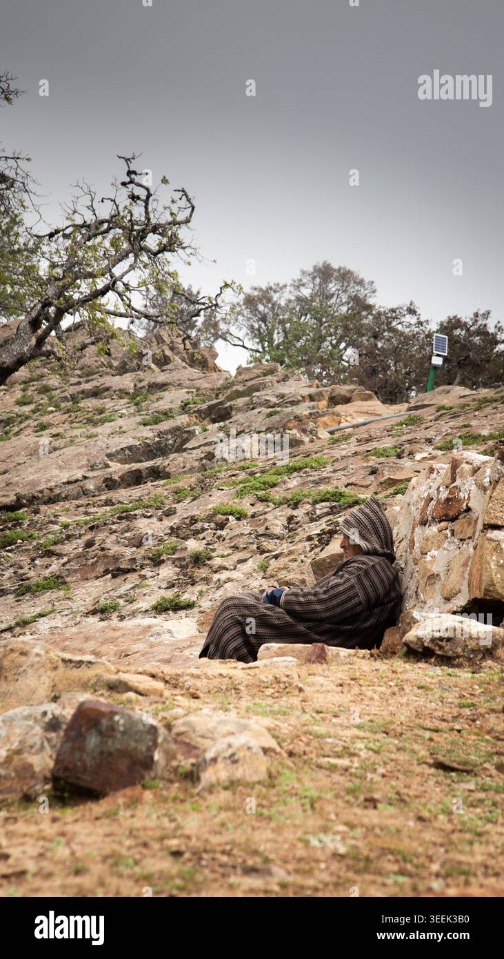 Larache, Maroc - mai, 04, 2026 : une figure solitaire reposant sur une pente rocheuse marocaine, incarnant la sérénité et la contemplation dans un cadre naturel dur Banque D'Images
