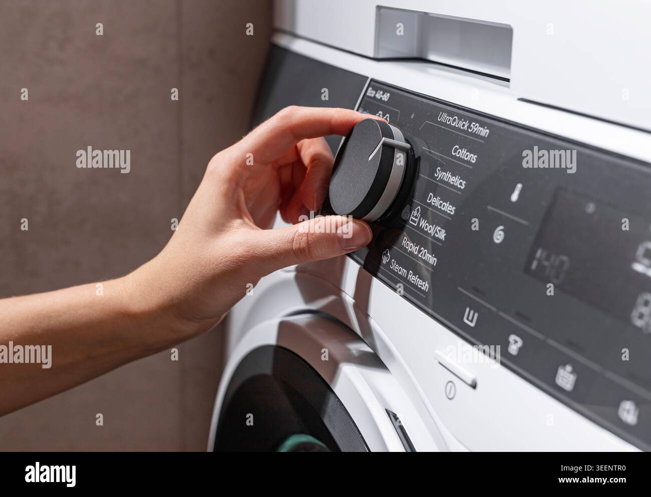 Main tourner le bouton de commande sur un panneau de machine à laver moderne, sélectionner un programme de blanchisserie sur une interface d'appareil numérique, vue rapprochée de ménage Banque D'Images