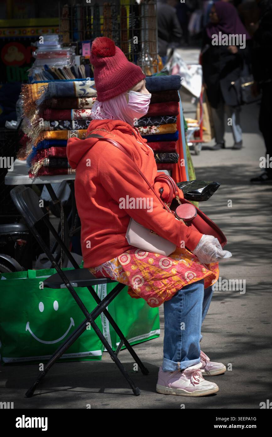 Une vendeuse musulmane portant un hijab, un niqab et des vêtements lumineux attend les clients de doserve sur un stand sur la 37e avenue à Jackson Heights, Queens, New York. Banque D'Images