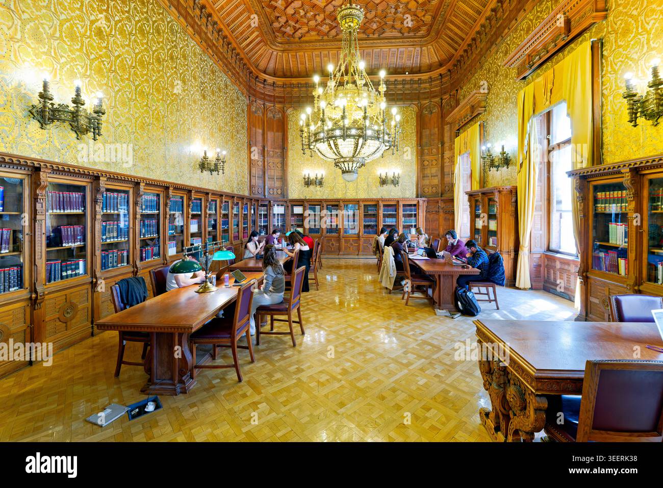 Les gens sont assis à des tables de lecture et d'étude dans la bibliothèque métropolitaine Ervin Szabo à Budapest, en Hongrie. Les livres sont sur les étagères autour de la pièce. Banque D'Images