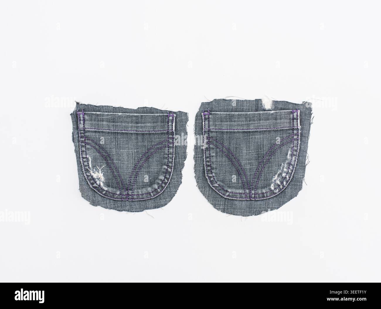 Gros plan de deux poches arrière en denim séparées avec des coutures violettes uniques et des signes d'usure. Isolé sur un fond blanc pour un design facile Banque D'Images