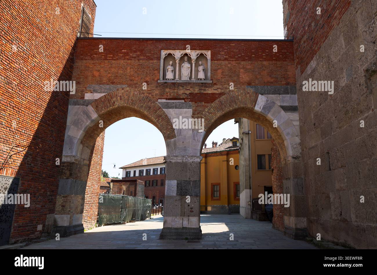 Porte historique en briques rouges ensoleillée avec deux grandes arches en pierre Banque D'Images