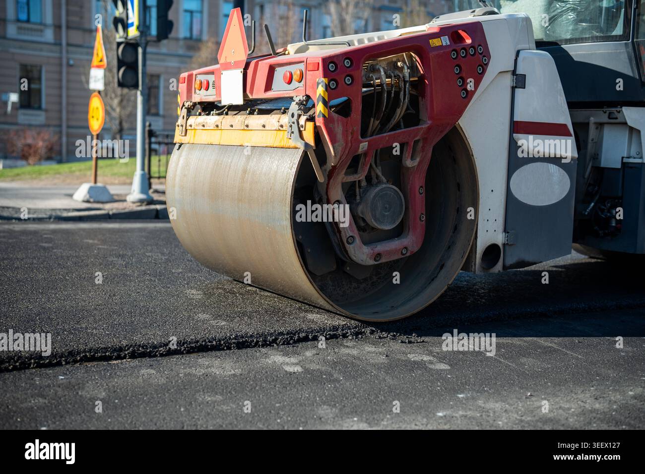 Machine à rouleaux lourds se déplaçant lentement sur une substance bitumineuse fraîchement posée et une surface lissante. Banque D'Images