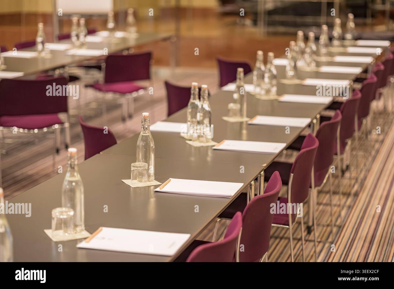 Salle de conférence avec tables, chaises, bouteilles d'eau et blocs-notes attendant les participants Banque D'Images