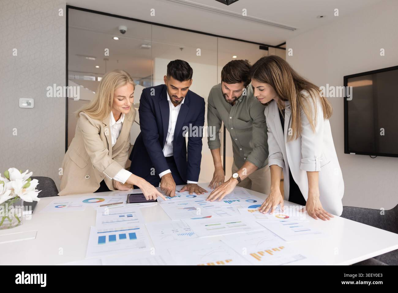 Groupe multinational examinant les graphiques pendant la réunion de bureau Banque D'Images
