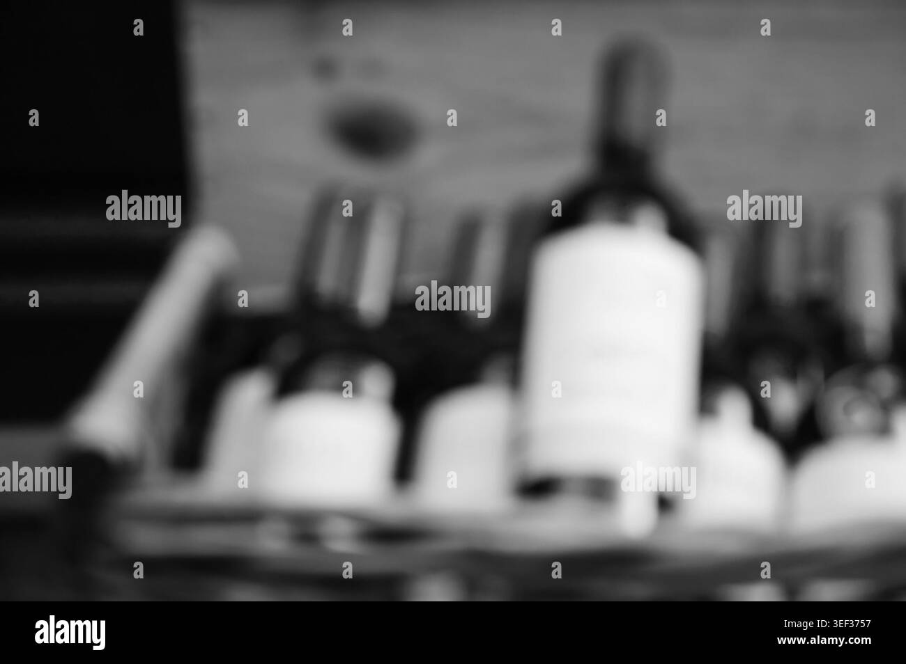 Vue floue de bouteilles de vin disposées dans une boîte en osier, évoquant la culture viticole française, le Beaujolais Nouveau et la vente au détail traditionnelle de vin en noir et blanc Banque D'Images