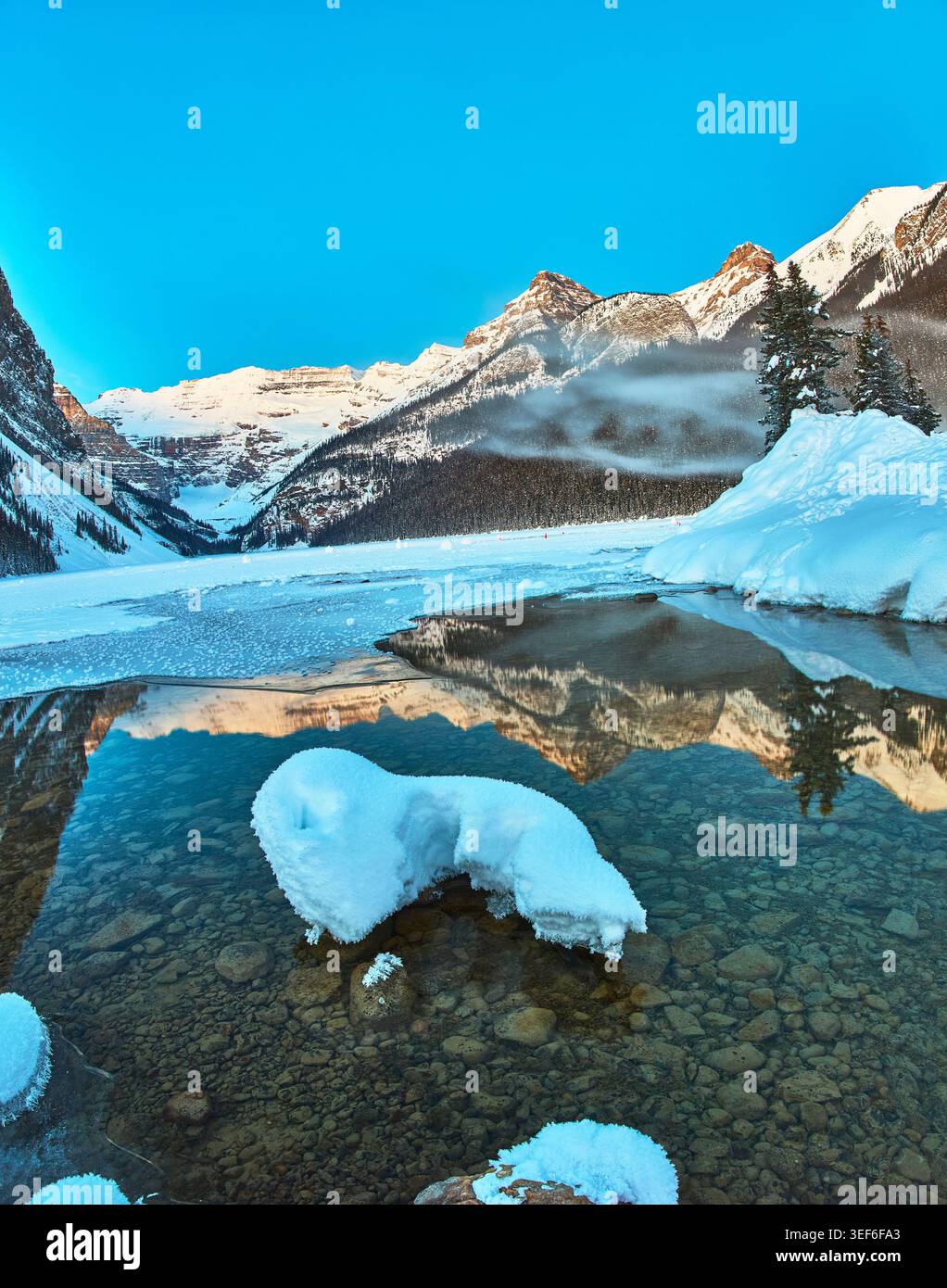 Vue panoramique hivernale sur les sommets enneigés du lac Louise et le ciel bleu clair Banque D'Images