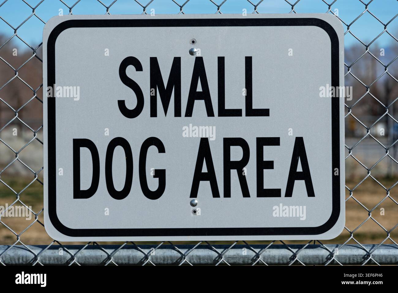 blanc et noir petit signe en métal de zone de chien sur la clôture de maillon de chaîne d'un parc de chien Banque D'Images