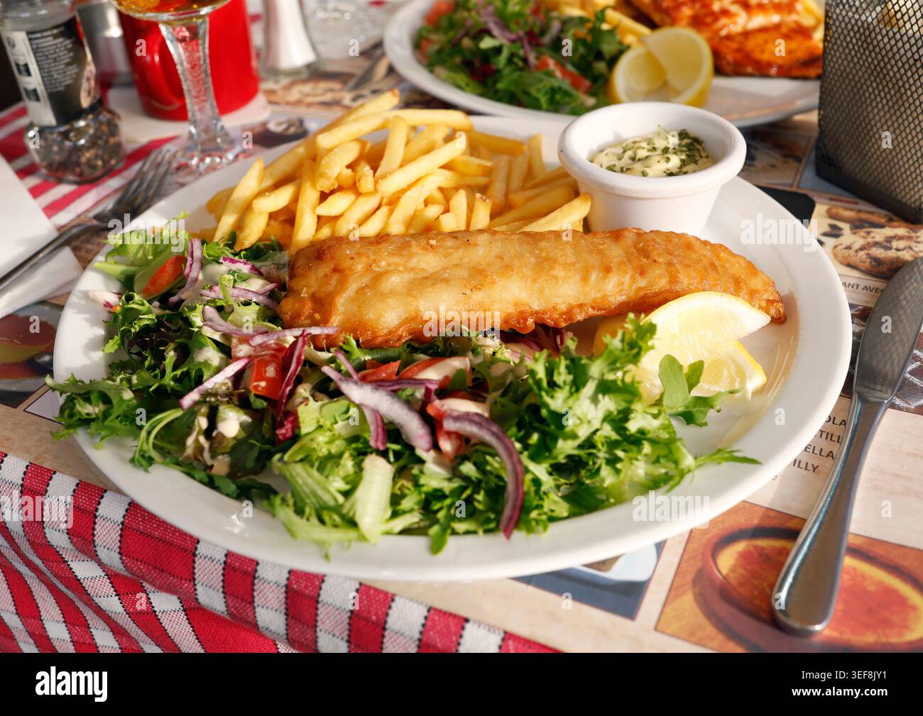 Le mélange de salade verte fraîche sert de plat d'accompagnement coloré sain pour le poisson frit doré. Feuilles de laitue croquantes mélangées avec du chou violet et mûres Banque D'Images