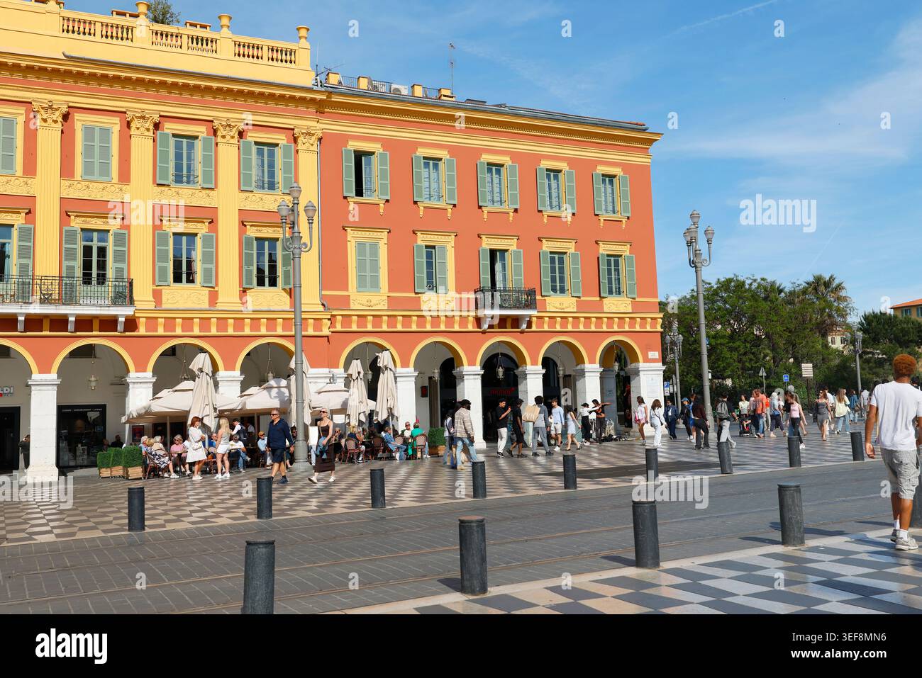 Nice, France - 8 mai 2026. La terrasse extérieure du restaurant Nice France place Massena accueille des touristes assis sous des parasols blancs. Ocre rouge historique Banque D'Images