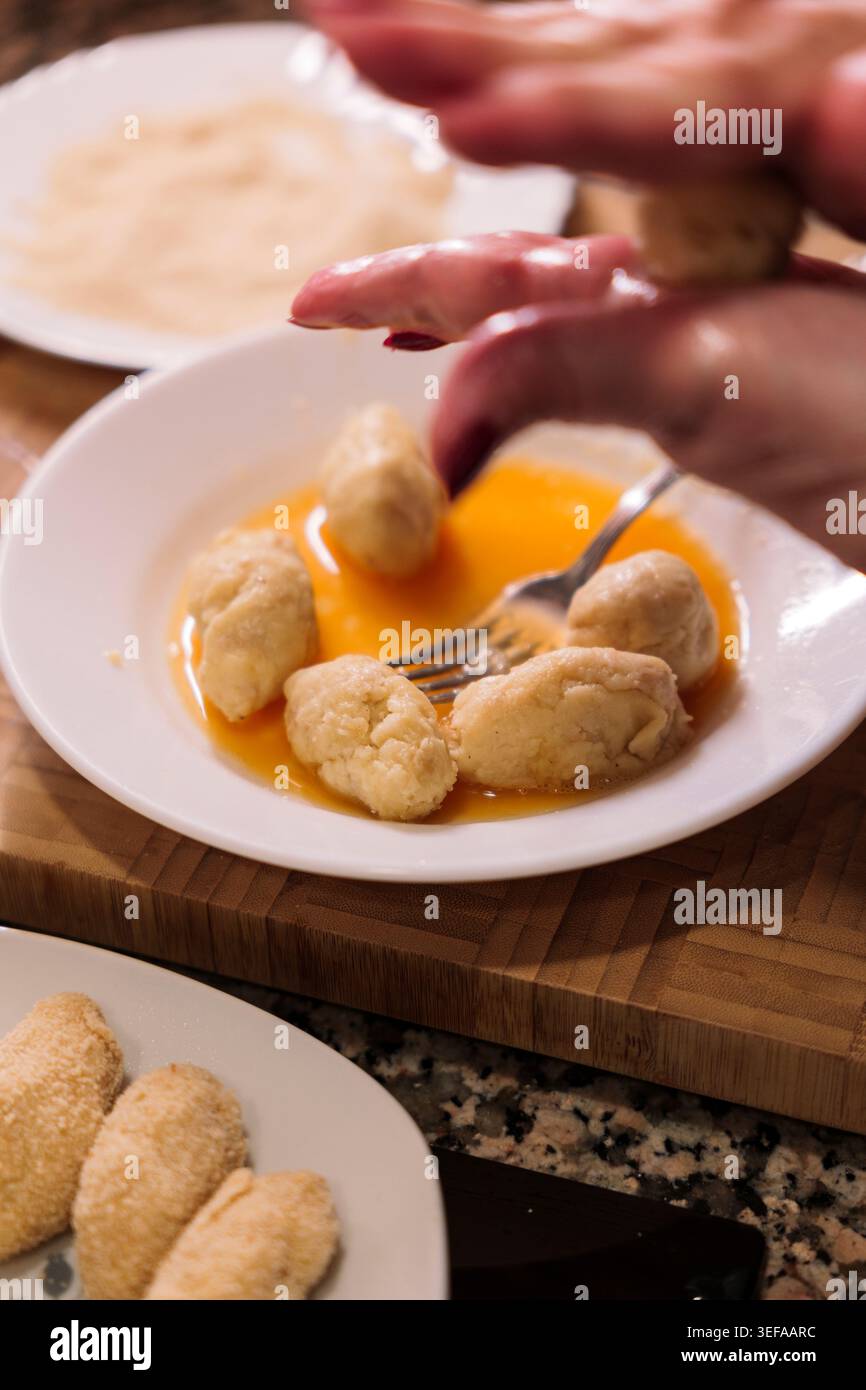 Croquettes préparation avec les mains façonner la pâte dans le lavage aux œufs et la chapelure. Croquetas espagnols faits maison. Banque D'Images