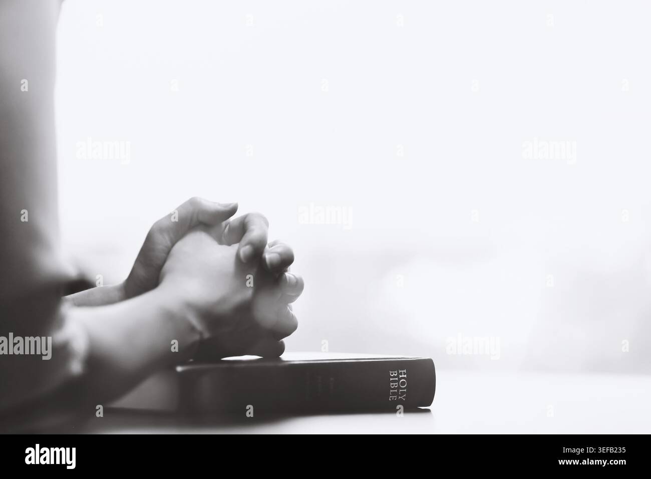 Le temps de prière pieux d'un chrétien, en plaçant les deux mains sur la Bible et en offrant des prières sincères dans le silence. Banque D'Images
