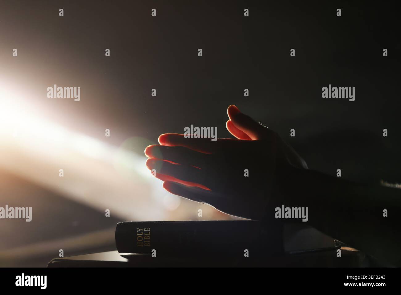 Un temps de prière pieuse illuminé par une lumière vive, la sainte Bible, et un arrière-plan de culte spirituel Banque D'Images