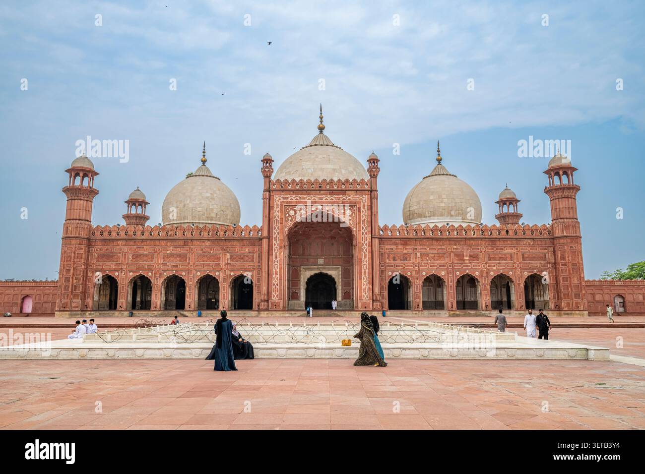 Les visiteurs explorent l'architecture de la mosquée Badshahi à Lahore sous le ciel dégagé Banque D'Images