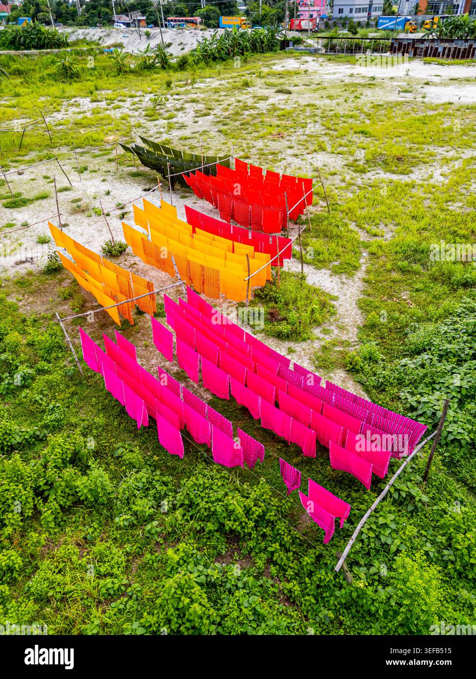 Vêtements fraîchement teints suspendus dans des couleurs vives dans le village d'Araihazar, Bangladesh près d'une zone herbeuse Banque D'Images