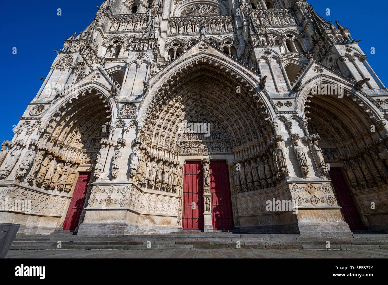 La cathédrale d'Amiens présente des sculptures détaillées et des arcades sous un ciel bleu clair en France Banque D'Images