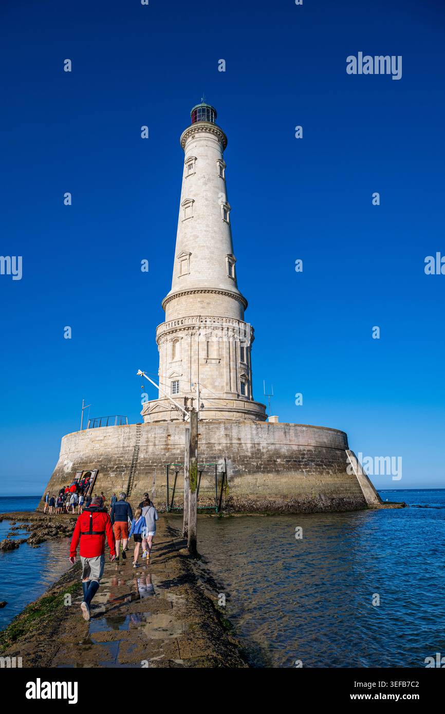 Les visiteurs marchent le long du chemin menant au phare de Cordouan près de l'océan en France par temps clair Banque D'Images