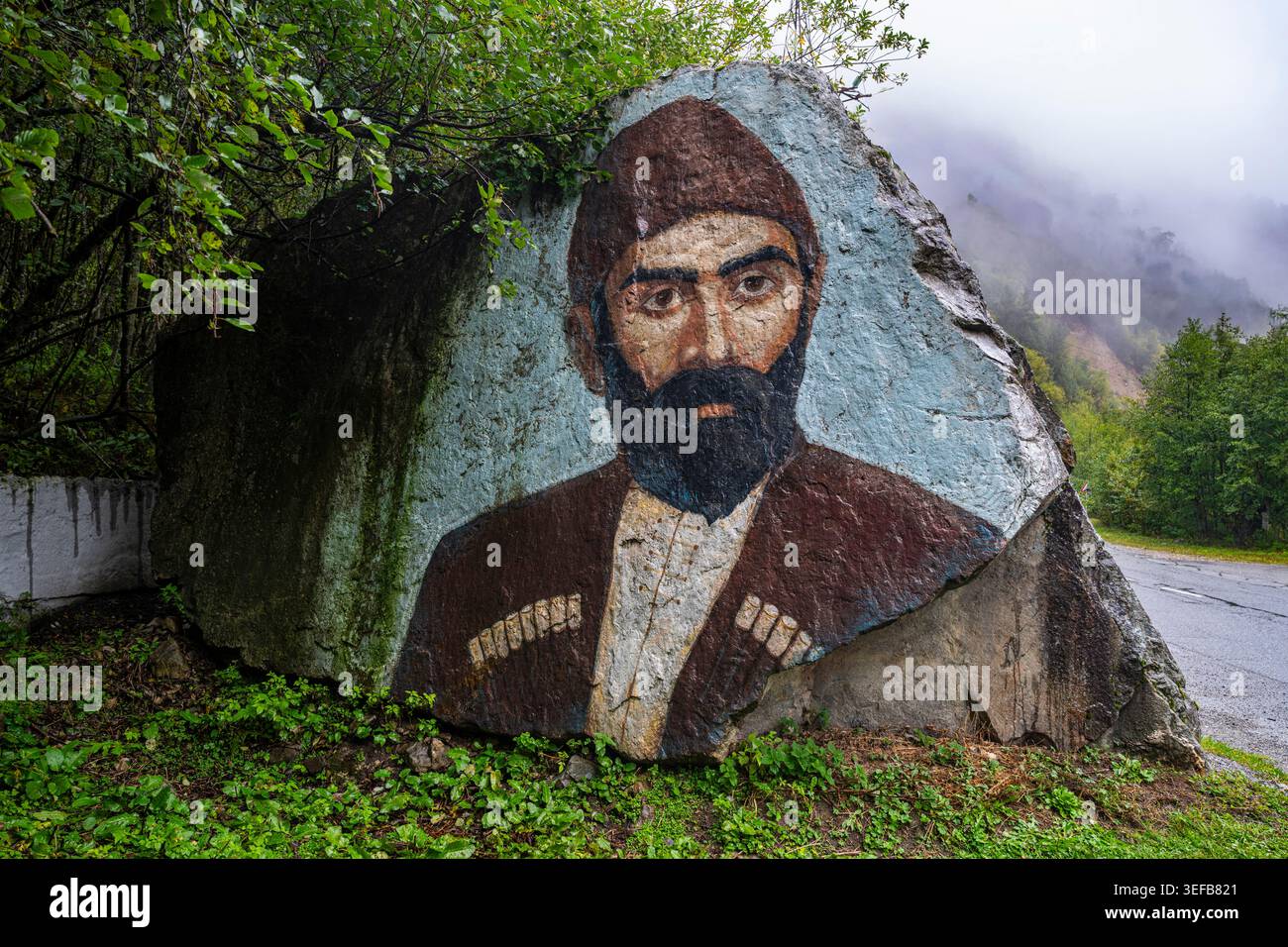 Artiste créant une murale sur un grand rocher en Ossétie du Nord, mettant en valeur la culture et le patrimoine locaux en Russie Banque D'Images