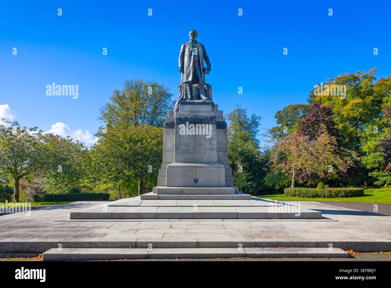Statue d'Andrew Carnegie dans le parc Pittencrieff à Dunfermline, Fife, Écosse, avec ciel bleu clair et arbres Banque D'Images