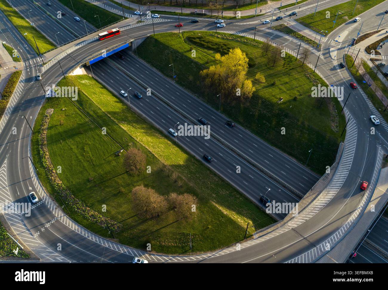 Vue aérienne d'un échangeur autoroutier à plusieurs niveaux avec circulation et un bus rouge conduisant sur des routes asphaltées entourées d'herbe verte et d'arbres à Vilnius Co Banque D'Images