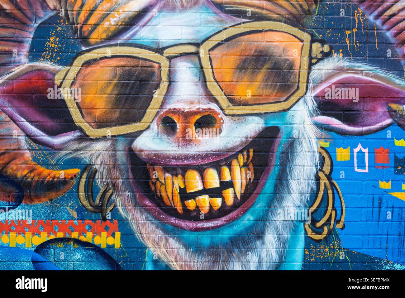 Murale urbaine dynamique représentant une chèvre stylisée portant des lunettes de soleil et des écouteurs, peinte sur un mur à Brighton Banque D'Images