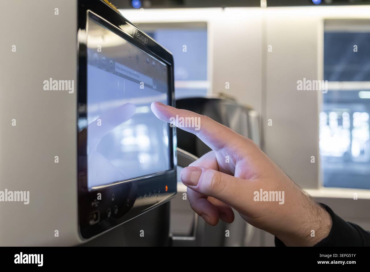 Une personne utilise un écran d'affichage interactif de dossier de siège sur un véhicule, illustrant l'engagement continu d'un passager avec le multimédia de voyage, l'entertai numérique Banque D'Images