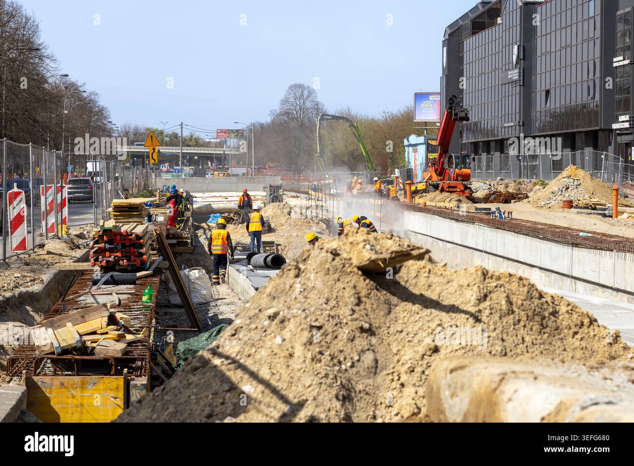 Varsovie, Pologne - 13 avril 2026 : une équipe de construction travaille sur un projet routier urbain avec de l'équipement lourd et un sol poussiéreux pour représenter l'infra essentiel Banque D'Images