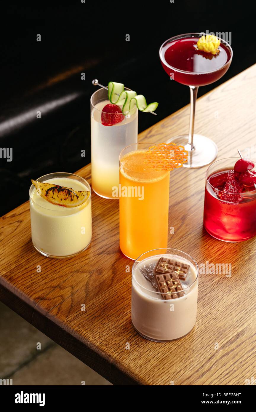 Un assortiment de cocktails colorés sur un plateau de bar en bois Banque D'Images