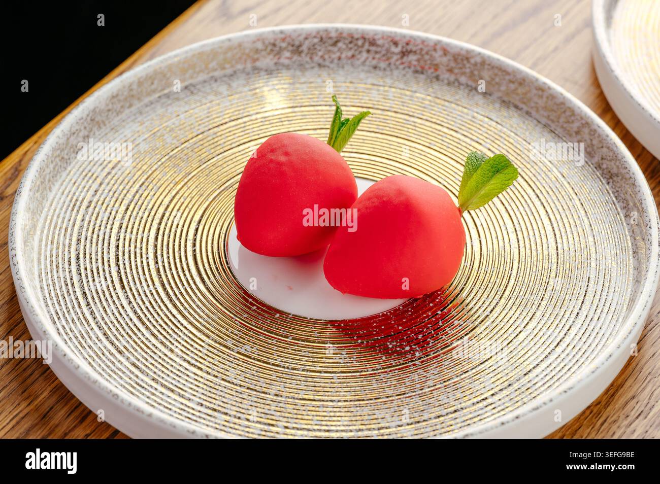 Deux desserts en mousse en forme de radis sur une plaque d'or Banque D'Images