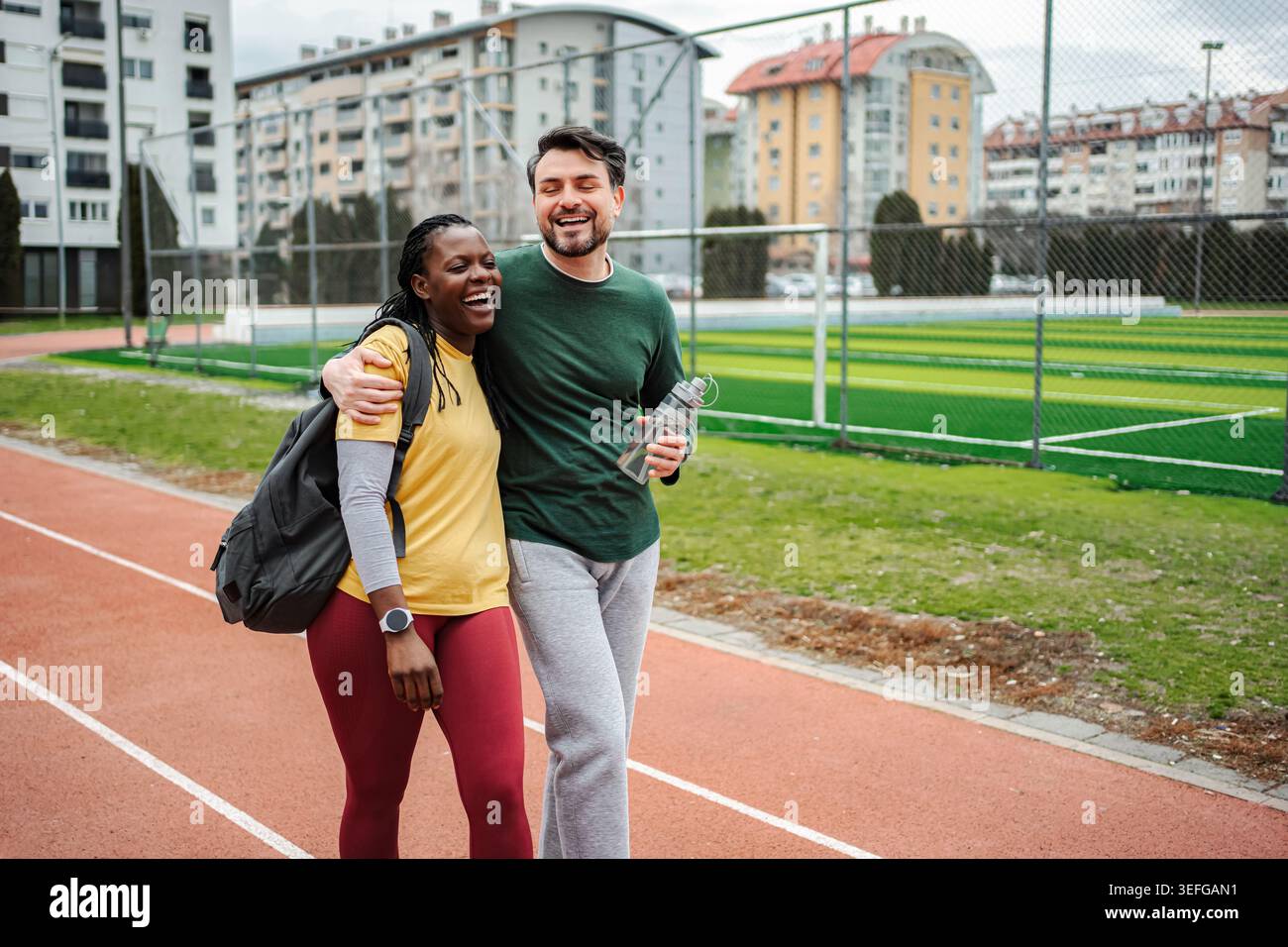 Un couple rigolant embrassant la piste de marche après l'entraînement Banque D'Images