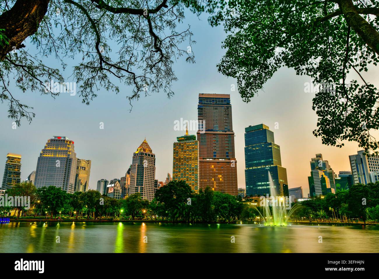 Horizon de la ville au crépuscule avec des reflets sur le lac et des gratte-ciel modernes du parc Lumphini, Bangkok, Thaïlande. Banque D'Images