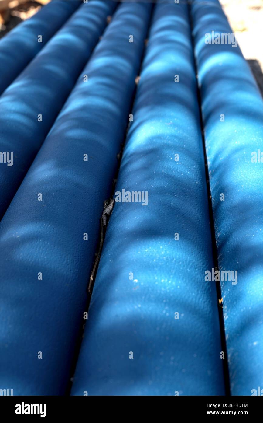 Motif abstrait gros plan de tubes d'isolation de tuyau en mousse bleue sous la lumière du soleil brillante avec des ombres douces. Banque D'Images