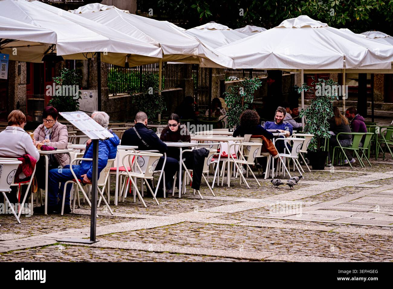Aveleda, Porugal -- 14 avril 2026. Photographie de rue franche des gens dînant dans un café en plein air sous des parasols blancs dans une charmante ville portugaise Banque D'Images