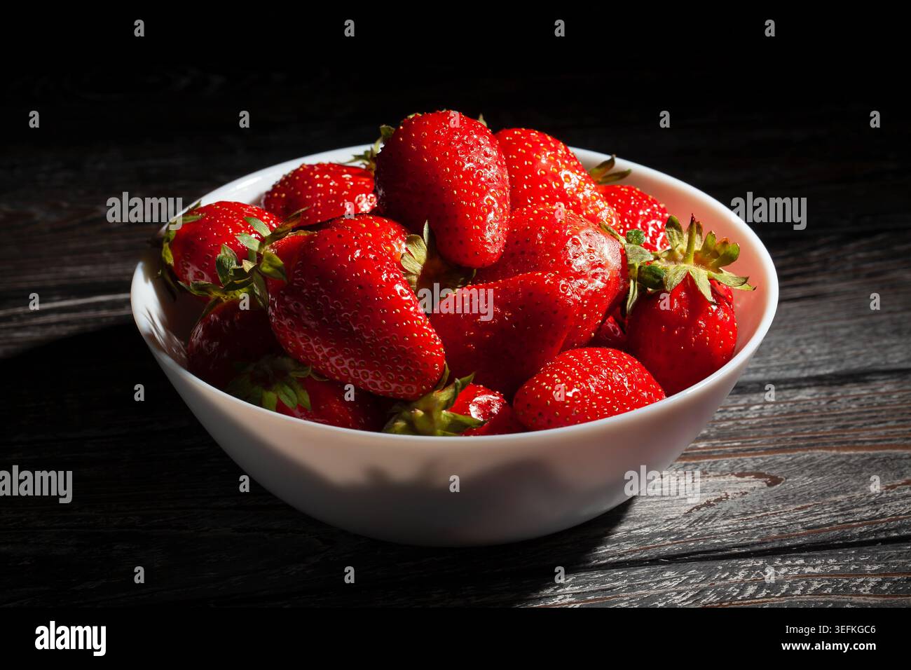 bol de fraise sur fond de bois noir Banque D'Images