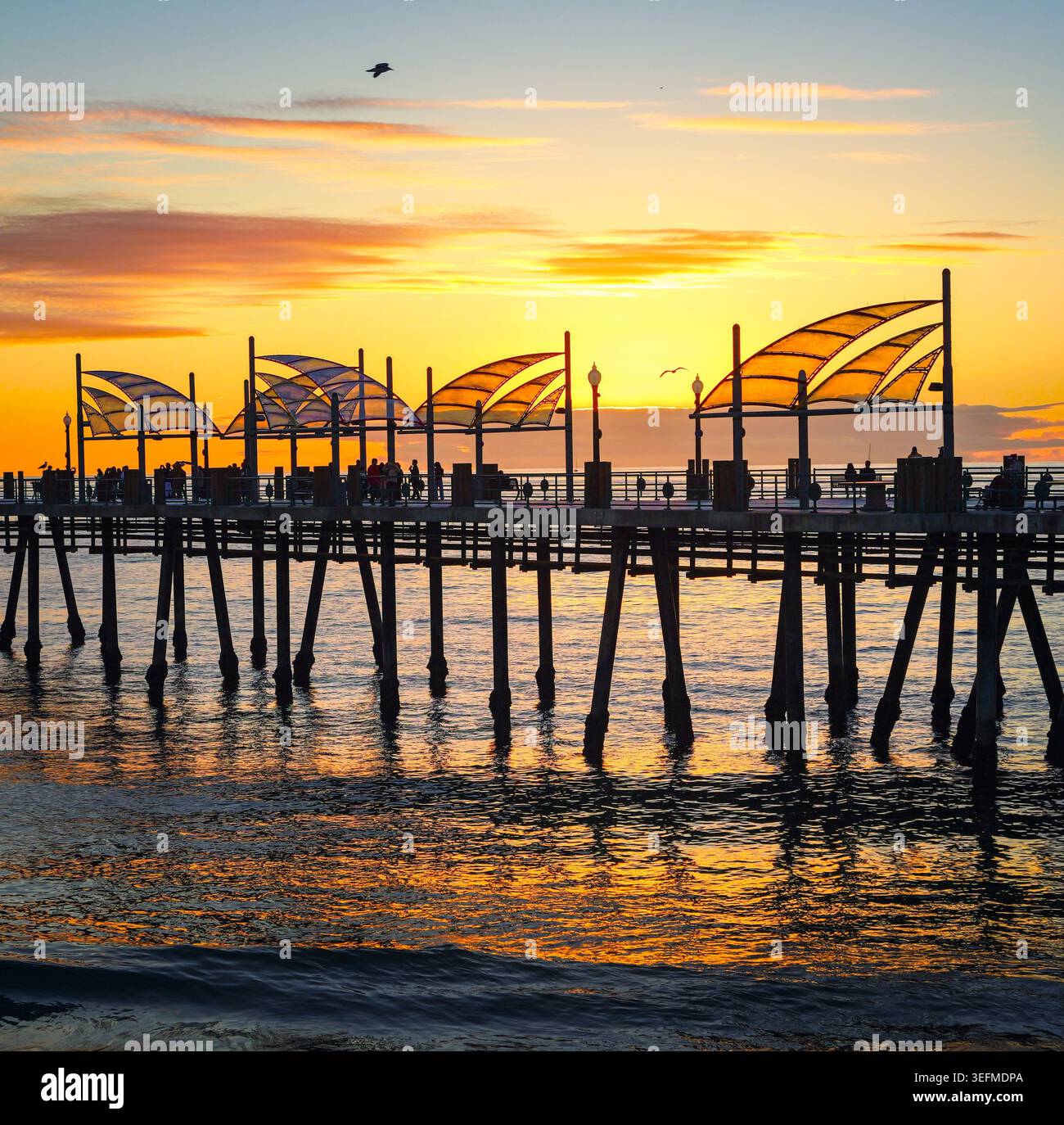 Redondo Beach Pier au coucher du soleil avec des reflets océaniques et une structure silhouette le long de la côte californienne. Banque D'Images