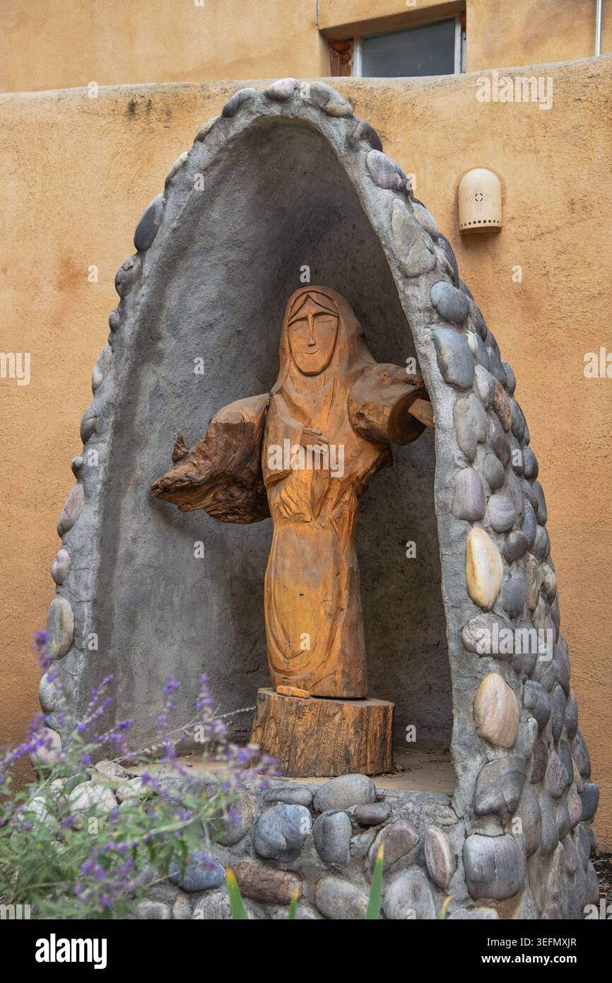 Une figure artisanale en bois sculptée à la main est nichée dans une arche en pierre dans la cour de l'église catholique de Joseph - Iglesia de San Jose in Cerrillos Banque D'Images